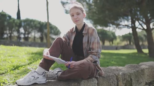 Young Woman Writing Outdoors in a Park