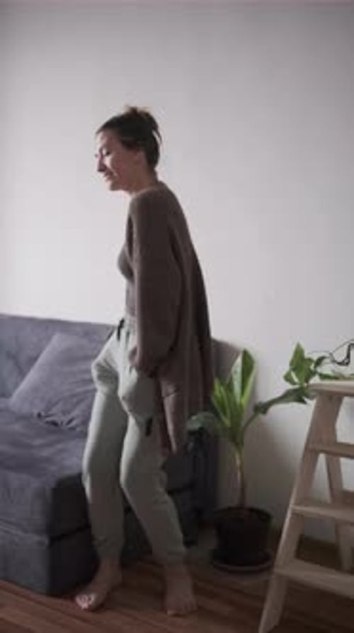 Woman Posing Barefoot Indoors by Couch and Plant