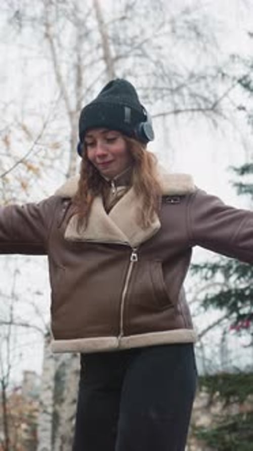 Smiling Girl Balancing on Stone Path with Outstretched Arms in Autumn