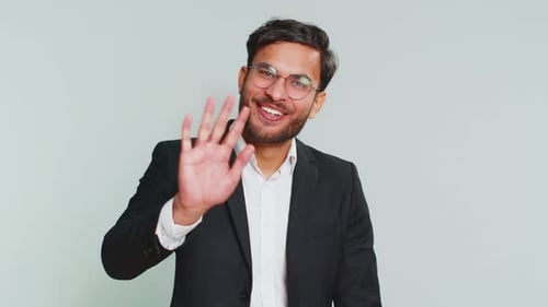 Smiling Young Adult Waving Hello and Making Call Gesture