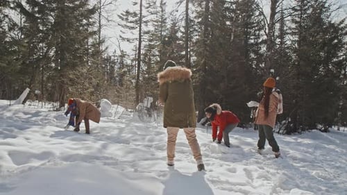 Friends Enjoying Snowball Fight in Winter Forest