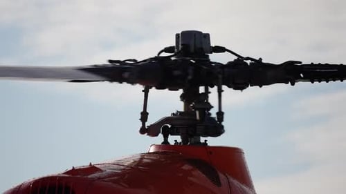 Closeup View of a Red Helicopter Main Rotor Assembly in Motion and Coming to Rest Highlighting the