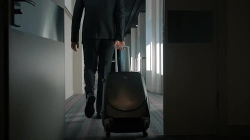Businessman arriving at hotel with suitcase for business trip slow motion