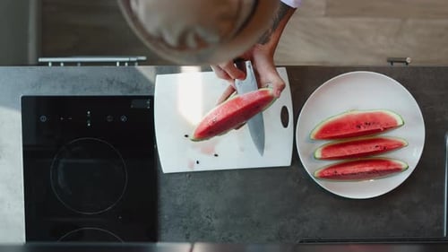 Professioneller Koch schneidet eine Wassermelone gekonnt in perfekte Würfel auf einem weißen Schneidebrett in einem