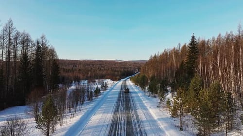 Militärlastwagen fährt auf verschneiter Straße im Winterwald