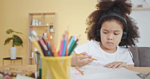 Girl with Headphones Drawing at Home