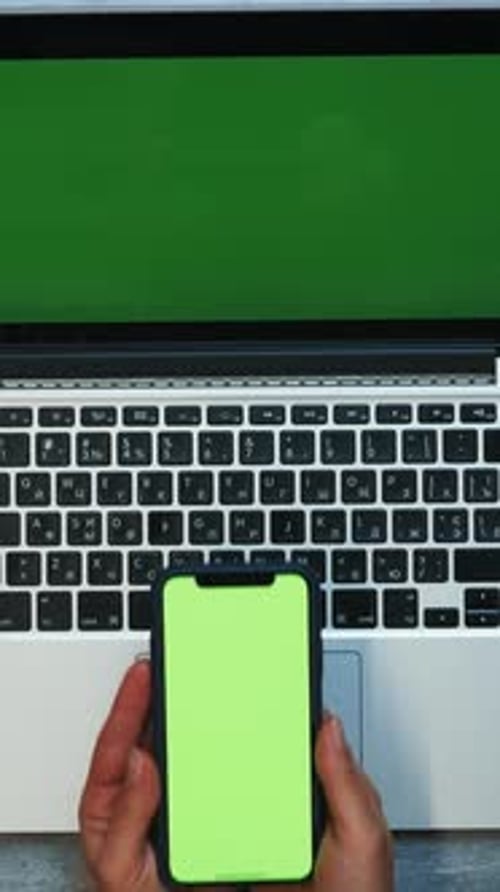 Top view of female hands holding smartphone with green screen. Vertical video