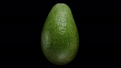 Precisely Cut Avocado Half with Pit Rotates on a Black Background in Close-up. Isolated, Looping.