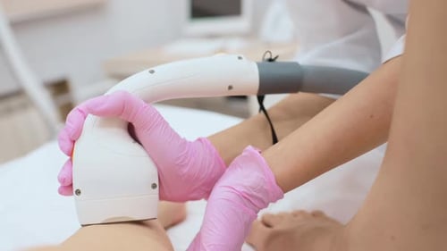 Cosmetologist Performs Laser Hair Removal of the Patient's Legs in a Modern Cosmetology Clinic