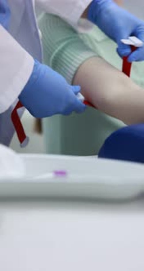 Doctor in protective gloves putting medical tourniquet and disinfecting patient's arm