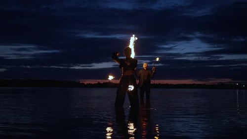 Professional Stuntwoman And Stunt Man Performing Tricks With Fire Amazing Fire Show On River Coast