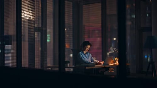Woman Works Late Night on Laptop in Office