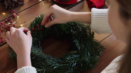 Woman Decorating Festive Holiday Wreath with Red Berries