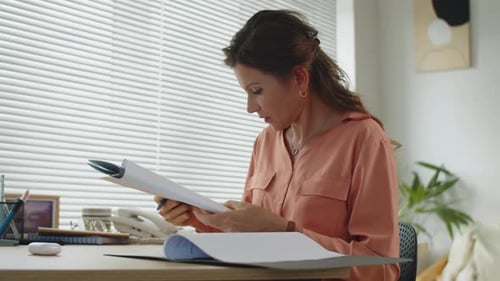 Serious Female Lawyer Editing Business Contract at Table