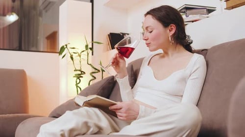 Woman Enjoys Wine While Reading Book at Home