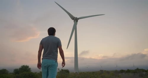 Vista trasera de un joven que se opone al negocio de la industria eléctrica en el desarrollo de los molinos de viento