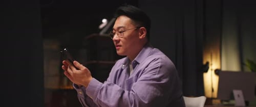 Man Looking at Phone While Sitting Indoors