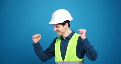 Positive Happy Foreman Wearing Safety Hard Hat and Green Vest Dancing Isolated on Blue Background