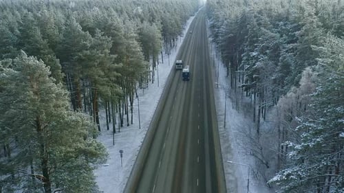 Verschneiter Winter-Roadtrip durch einen dichten Wald mit Lastwagen, die auf der Autobahn in Finnland fahren