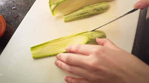 Slow motion female hands slicing a green zucchini in the kitchen in slow motion
