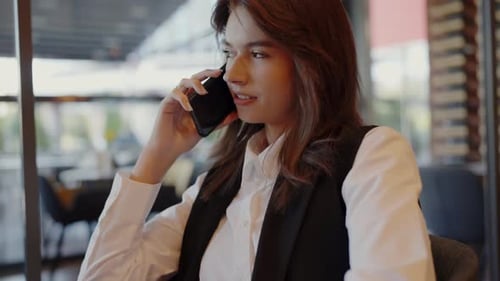 Woman Speaking on Mobile Phone in Cafe