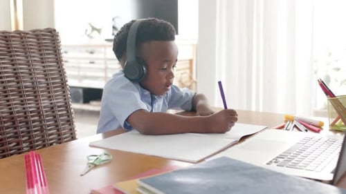 Child with headphones writing in notebook