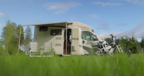 RV with Lawn Chairs and Bicycles in Meadow