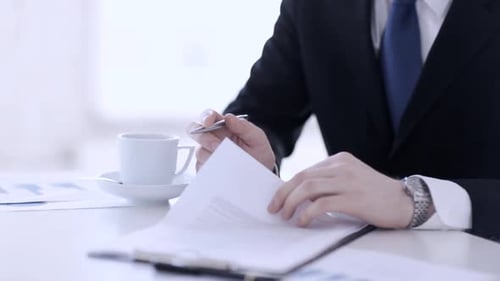 Businessman in suit signing important contract in bright modern office