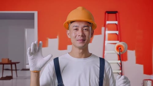Nahaufnahme eines asiatischen Malers, der lächelt und Wow sagt, während er die Wand im Zimmer malt