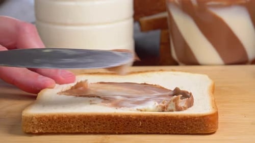 Hand Spreads Chocolate and White Spread on Bread