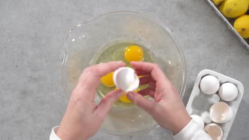 Cracking fresh eggs into glass bowl for baking