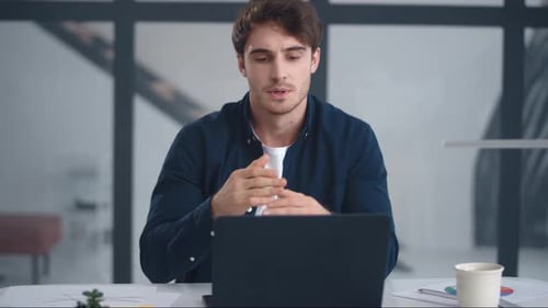 Young Man Video Conferencing at Desk in Modern Office