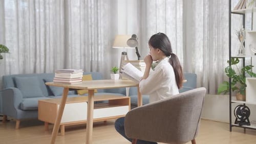 Back View Of Tired Asian Teenager Yawning And Sleep On The Table At Home After Doing Home Work