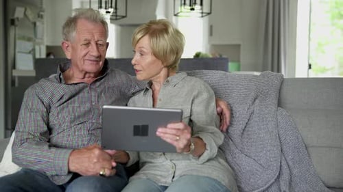 Senior Couple Relaxing on Couch with Tablet Indoors