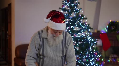 Senior Man Decorates Christmas Tree with Gift