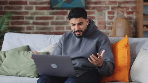 Irritierter Mann, der während eines Videoanrufs mit dem PC verzweifelt schreit