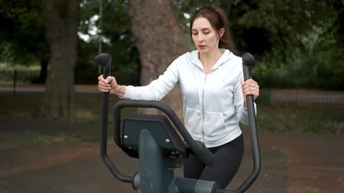 Woman Engaged in Outdoor Fitness Routine Using Exercise Equipment in Park Setting During Daylight