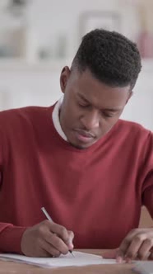 African Man Writing on Paper in Office, Vertical Video
