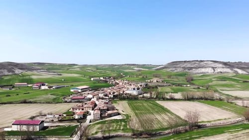 Imagens aéreas de uma cidade europeia cercada por campos verdes e marrons