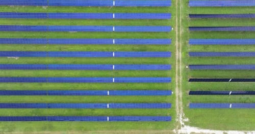 Aerial View of Solar Panels in a Green Field
