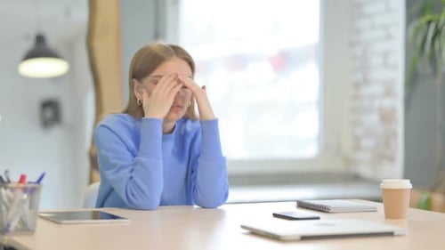 Worried Young Woman Sitting at Desk in Office