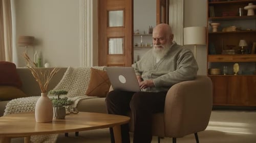 Senior Man Using Laptop in Bright Living Room