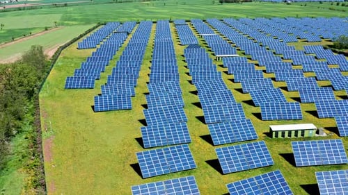 Rows of solar panels on a sunny day in a green field, aerial view