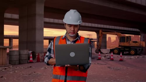Asian Male Engineer Working On A Laptop At Building Site
