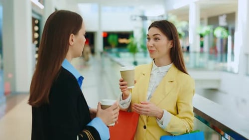 Two Happy Female Friends Standing in the Shopping Mall