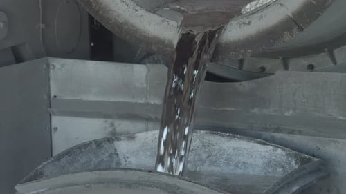 Nahaufnahme von geschmolzenem Aluminium in Zeitlupe, das in einen großen Behälter gegossen wird