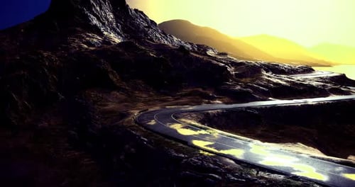 Winding Road Through Rugged Terrain at Dusk Under Golden Sunlight