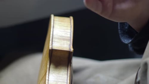 Expert Craftsman Applying Rich Amber Varnish to a Newly Crafted Violin Body in a Detailed Close Up