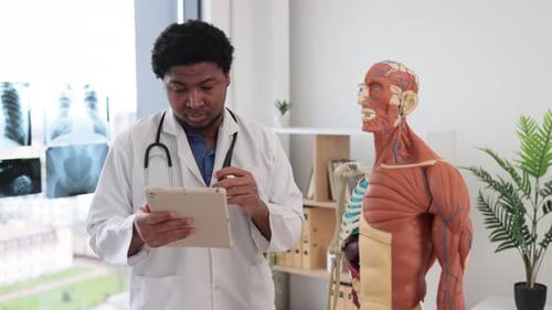 Physician Analyzing Shoulder Joint with Gadget in Clinic