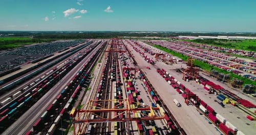 Bird's eye view of a rail terminal with containers and loading cranes.